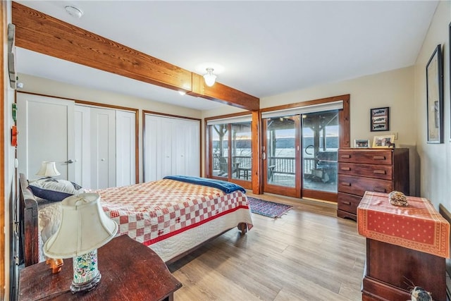 bedroom featuring beamed ceiling, two closets, light wood-type flooring, and access to outside