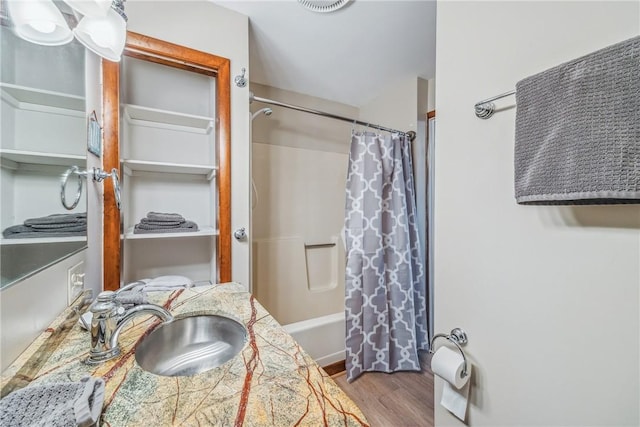 bathroom with hardwood / wood-style floors, shower / bath combo, and sink