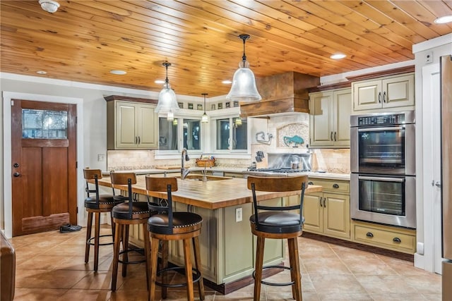 kitchen with a kitchen island with sink, hanging light fixtures, stainless steel appliances, decorative backsplash, and a breakfast bar