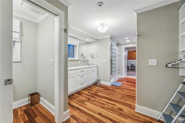 bathroom featuring vanity, backsplash, hardwood / wood-style flooring, and crown molding