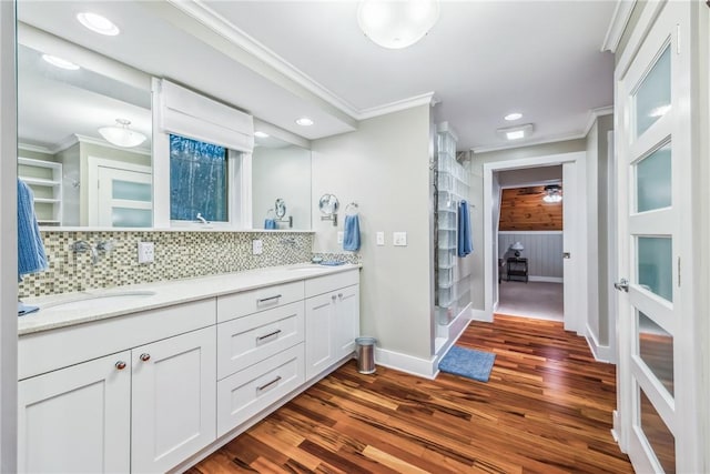 bathroom with vanity, wood-type flooring, ornamental molding, and tasteful backsplash