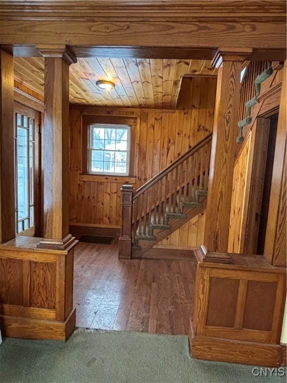 foyer entrance featuring dark hardwood / wood-style floors, wood walls, wood ceiling, and decorative columns