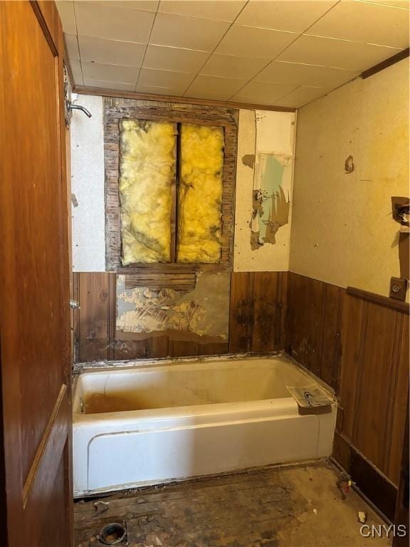 bathroom with wood walls and a bath