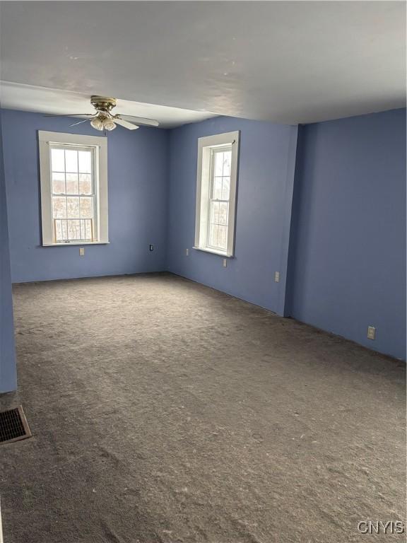 carpeted empty room featuring plenty of natural light and ceiling fan