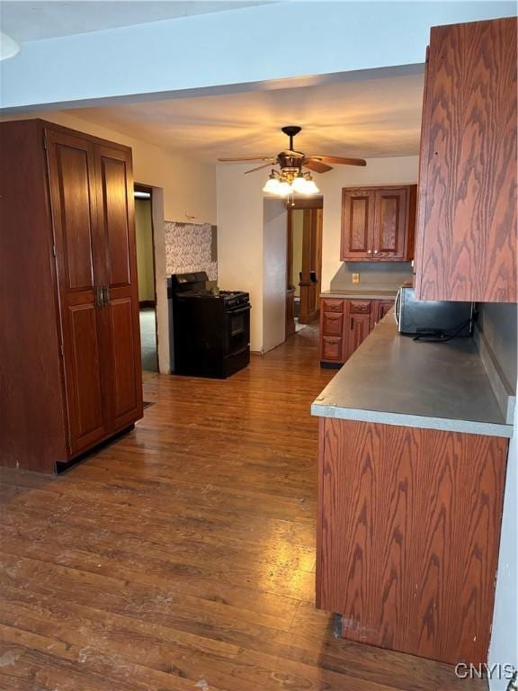 kitchen featuring black range oven, ceiling fan, and dark hardwood / wood-style flooring