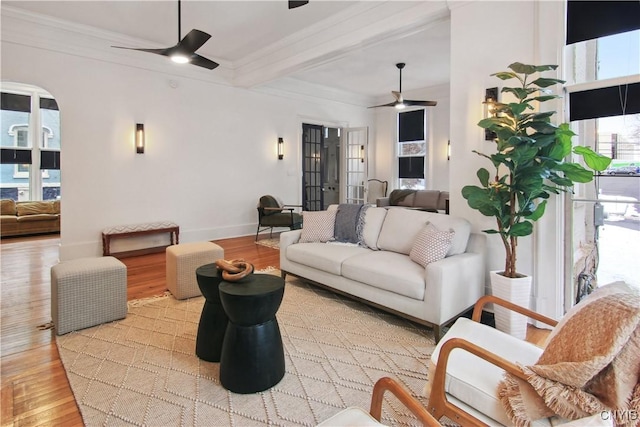 living room featuring ceiling fan, french doors, beamed ceiling, crown molding, and light wood-type flooring