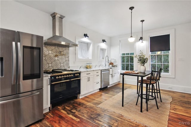 kitchen featuring tasteful backsplash, stainless steel appliances, wall chimney range hood, white cabinets, and dark hardwood / wood-style floors