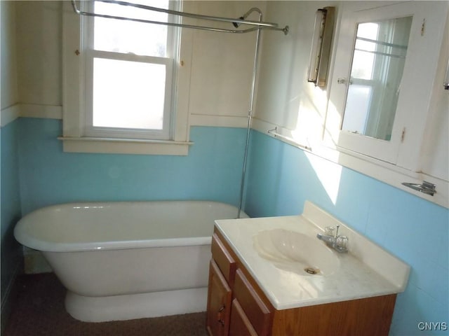 bathroom featuring a bath, vanity, and tile walls