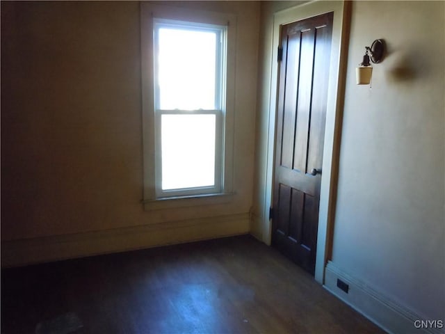 spare room with a wealth of natural light and dark hardwood / wood-style floors