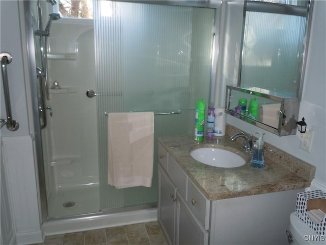 bathroom featuring vanity, toilet, and a shower with door