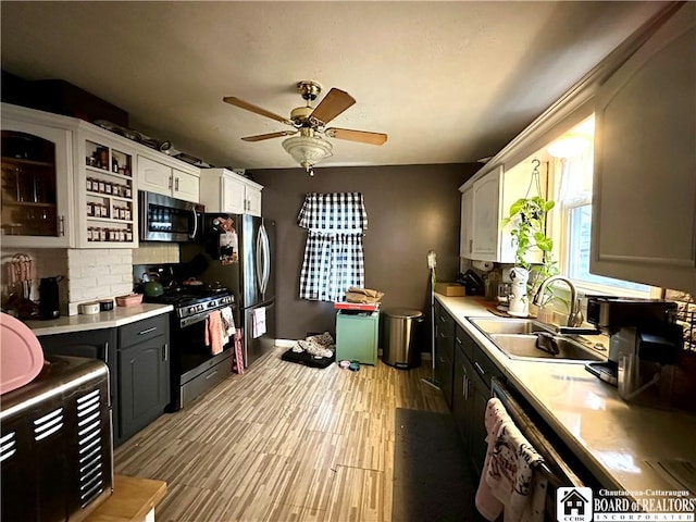 kitchen featuring backsplash, sink, appliances with stainless steel finishes, light hardwood / wood-style floors, and white cabinetry