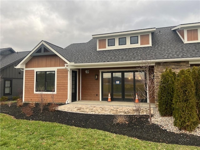 rear view of property with a shingled roof and a patio area