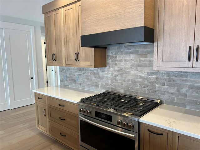 205 Charles Herrmann Way Unit 205, Milo, NY 14527 - kitchen with wall chimney range hood, light stone countertops, light wood-style floors, stainless steel gas stove, and decorative backsplash