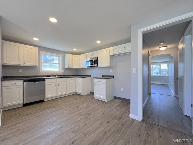 kitchen featuring appliances with stainless steel finishes, light hardwood / wood-style flooring, white cabinetry, and sink