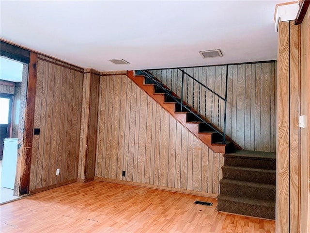 stairs featuring hardwood / wood-style floors and wood walls