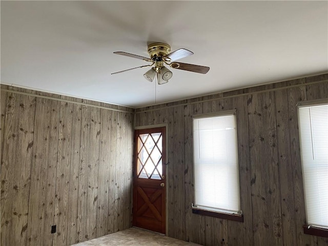 foyer with ceiling fan and wood walls