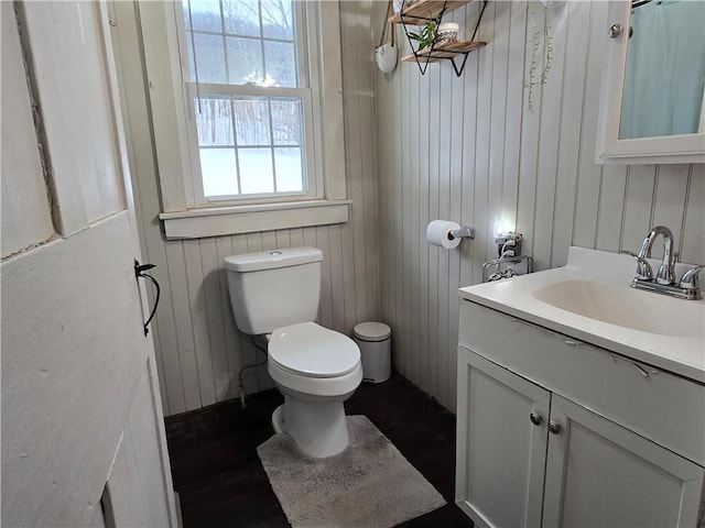 bathroom featuring hardwood / wood-style floors, vanity, toilet, and wooden walls