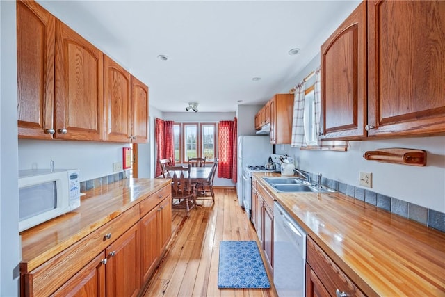 kitchen with butcher block countertops, sink, white appliances, and light wood-type flooring