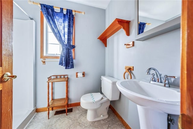 bathroom featuring a shower, toilet, and sink