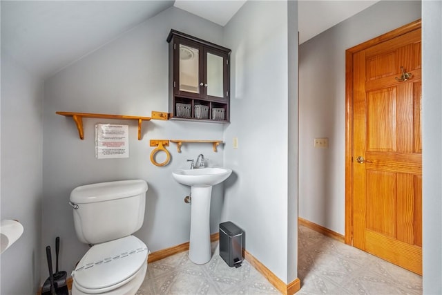 bathroom featuring toilet, sink, and vaulted ceiling