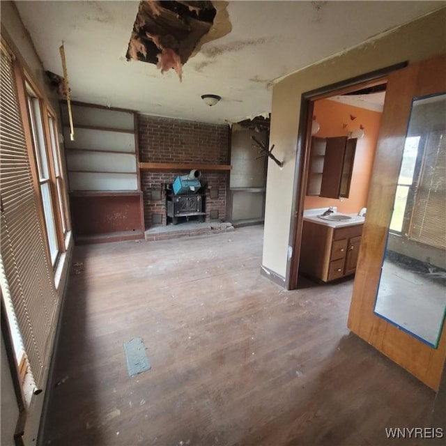 unfurnished living room with wood-type flooring, a wood stove, and sink