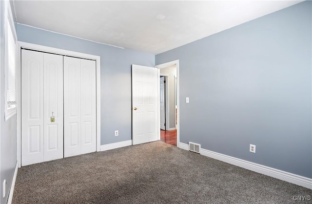 unfurnished bedroom featuring dark colored carpet and a closet