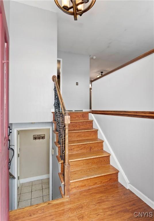 stairway with hardwood / wood-style floors and a chandelier