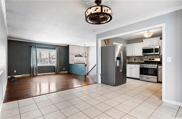 kitchen with decorative backsplash, appliances with stainless steel finishes, light wood-type flooring, crown molding, and white cabinets