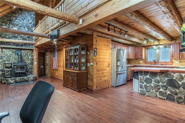 kitchen with a wood stove, stainless steel fridge, hardwood / wood-style floors, and wooden walls