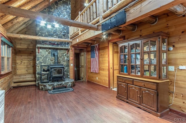 living room featuring wood-type flooring, vaulted ceiling with beams, a wood stove, and wooden walls