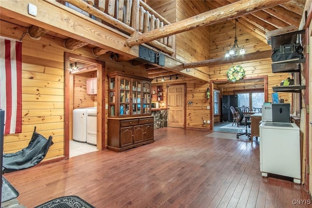 interior space with washer / dryer, lofted ceiling with beams, wooden walls, and hardwood / wood-style floors