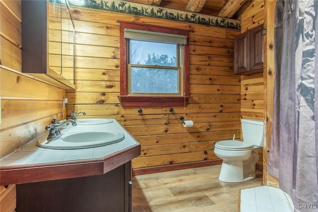 bathroom featuring beam ceiling, wood walls, wood-type flooring, toilet, and vanity