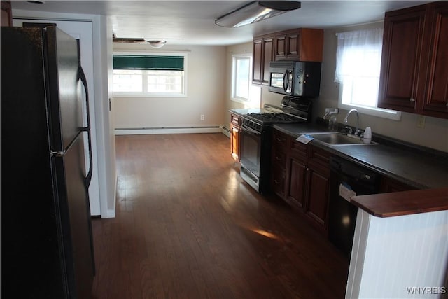 kitchen featuring dark hardwood / wood-style flooring, sink, a baseboard radiator, and black appliances