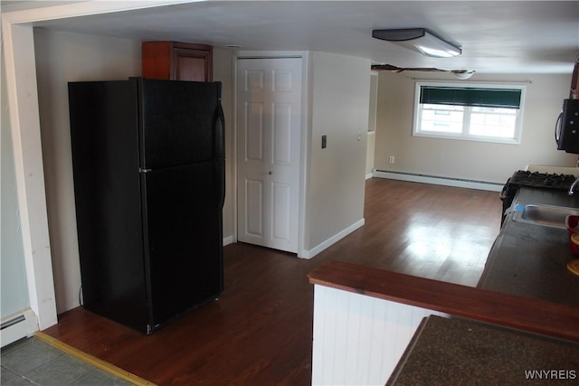 kitchen with baseboard heating, black fridge, sink, and dark wood-type flooring