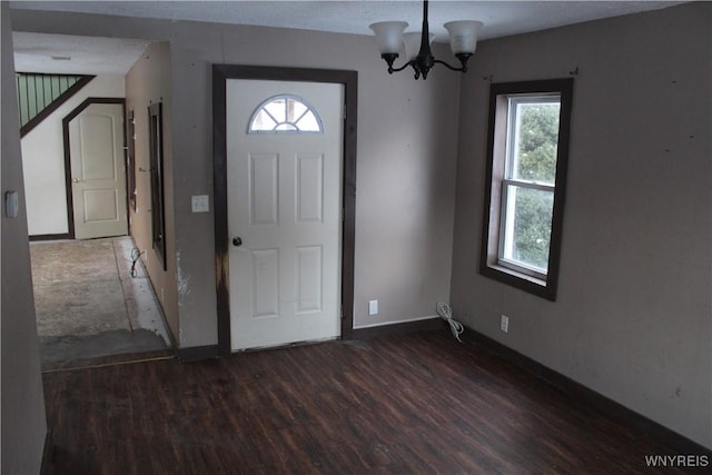 foyer entrance featuring a wealth of natural light, dark wood-type flooring, and a notable chandelier