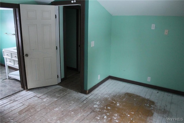 unfurnished bedroom featuring wood-type flooring and vaulted ceiling