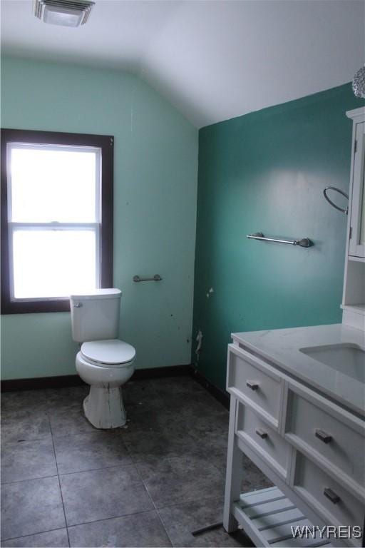 bathroom with tile patterned flooring, vanity, vaulted ceiling, and toilet