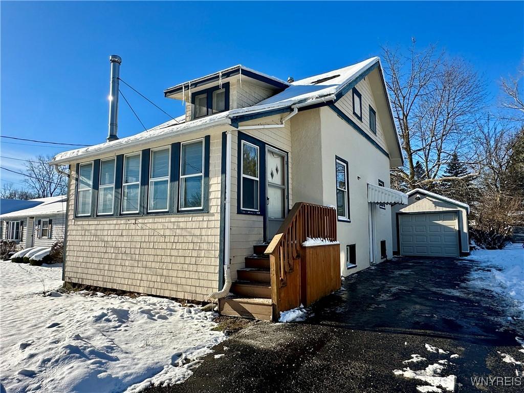 view of snowy exterior with a garage and an outbuilding