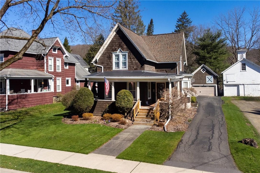 view of front of house featuring an outbuilding, a porch, a garage, and a front lawn