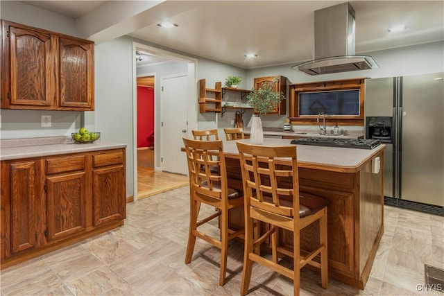 kitchen with stainless steel fridge, island range hood, a kitchen island, and a kitchen breakfast bar