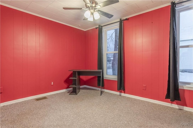 unfurnished office featuring ceiling fan, plenty of natural light, carpet, and ornamental molding