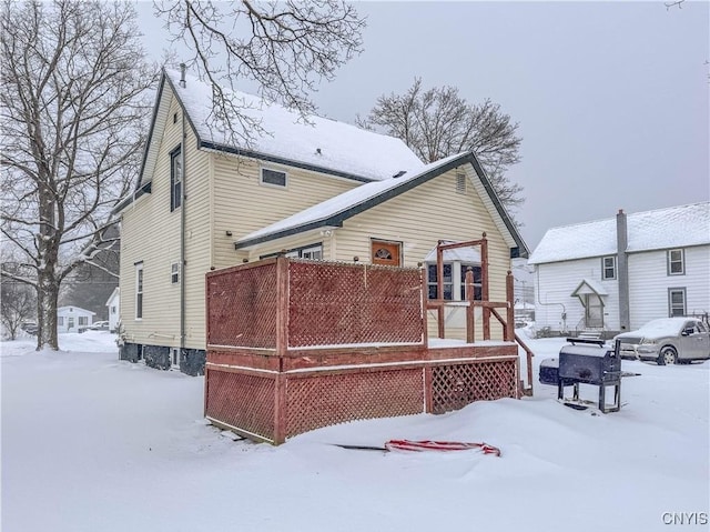 snow covered back of property with a wooden deck