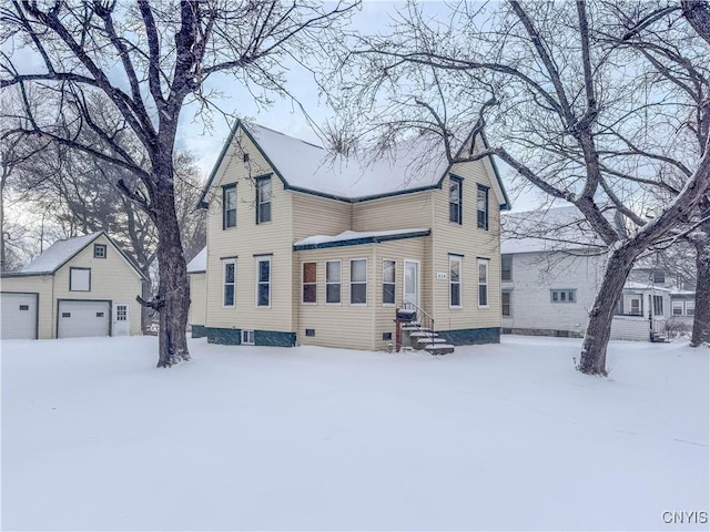 snow covered house featuring an outbuilding and a garage