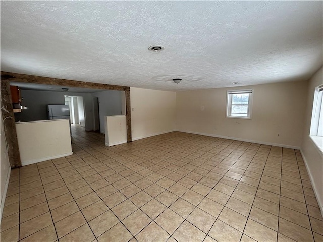 tiled empty room featuring a textured ceiling