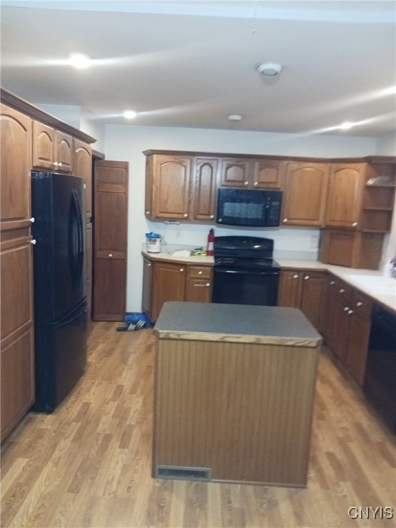 kitchen featuring black appliances, a kitchen island, and light wood-type flooring