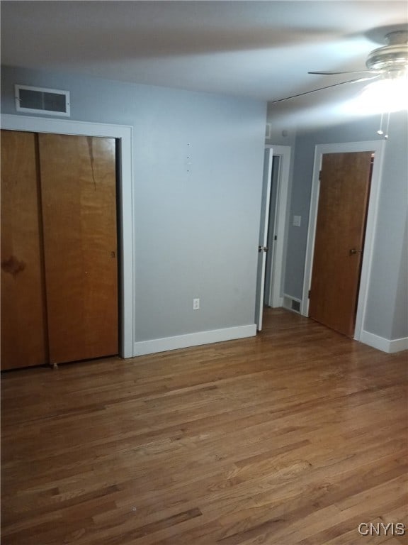 unfurnished bedroom featuring hardwood / wood-style flooring, ceiling fan, and a closet