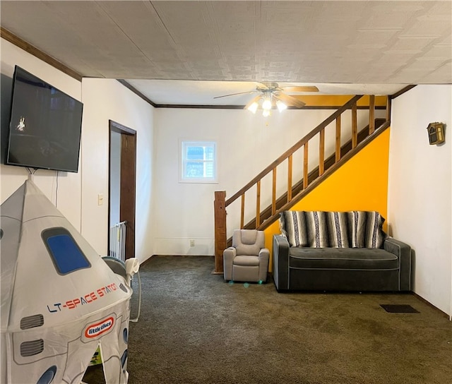 interior space featuring dark colored carpet, ceiling fan, and crown molding