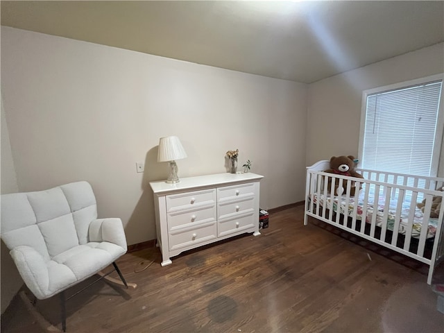 bedroom with dark hardwood / wood-style floors and a crib