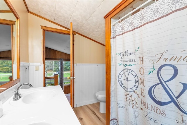 bathroom with crown molding, wood-type flooring, vaulted ceiling, toilet, and wooden walls