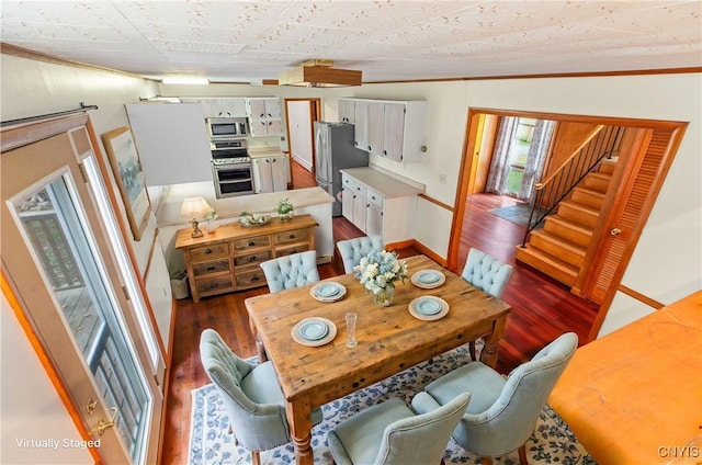 dining area featuring dark hardwood / wood-style floors, crown molding, and vaulted ceiling